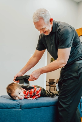 Chiropractor Lacey WA Mitchell Derrick With Happy Boy Adjusting Back With Tool