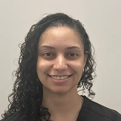 Chiropractic Lacey WA Megan Meet the Team Young woman with curly hair and a black shirt smiling